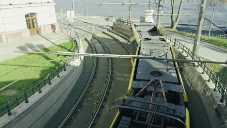 a tram in budapest making its way around a tight corner right next to the danube