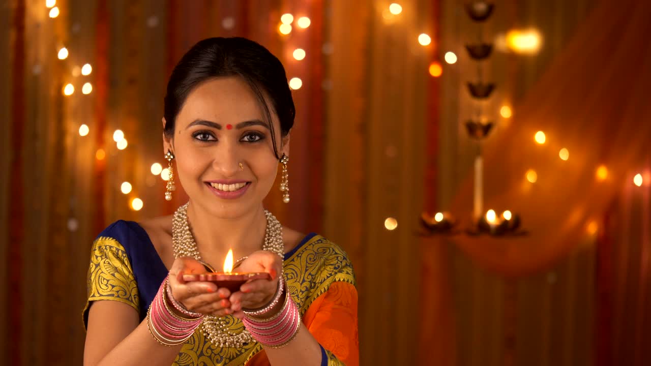 Traditional woman belonging to Hindu family lighting diya and bringing up in front of the camera - Diwali Invitation