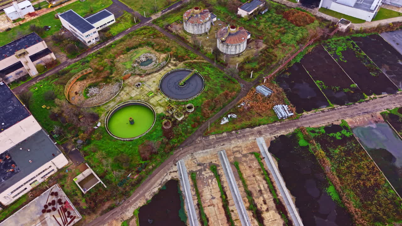 Abandoned industrial site with green water and empty buildings in daytime