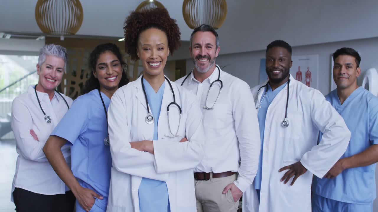 Portrait of diverse male and female doctors standing in hospital corridor smiling to camera