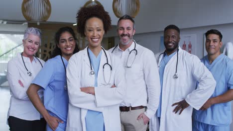 portrait of diverse male and female doctors standing in hospital corridor smiling to camera