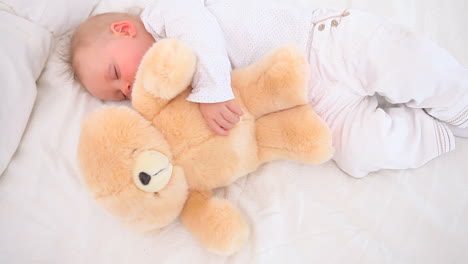 bebé durmiendo con un oso de peluche