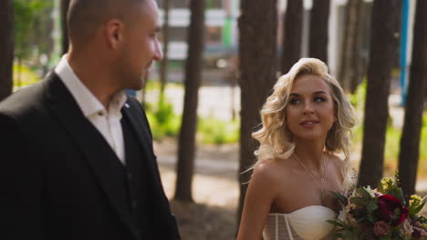 man in suit and woman in wedding dress walk along park