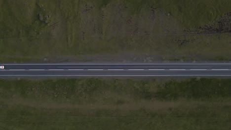 La-Noche-Desciende-Mientras-Los-Faros-Se-Abren-Camino-A-Través-De-La-Oscuridad,-Una-Toma-Cenital-Que-Sigue-El-Viaje-De-Un-Automóvil-Solitario-Por-Una-Carretera-Recta-Y-Apartada.