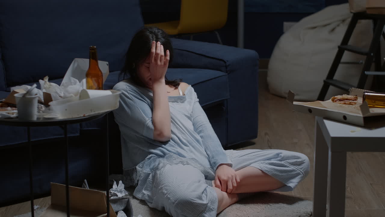 Depressed young woman sitting alone on floor crying looking at camera