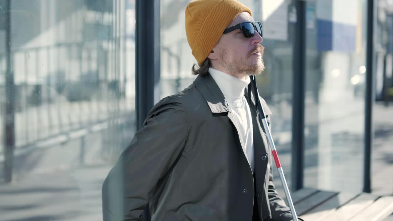 시내 버스 정류장에 앉아 있는 시각장애인.