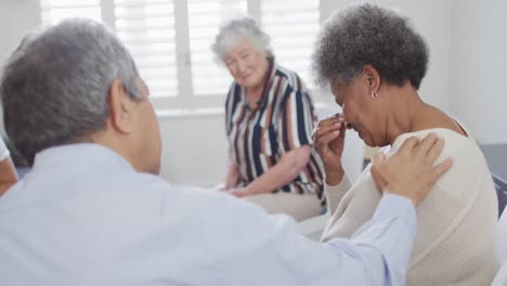 Diverse-group-of-senior-friends-giving-support-to-african-american-female-friend-on-meeting