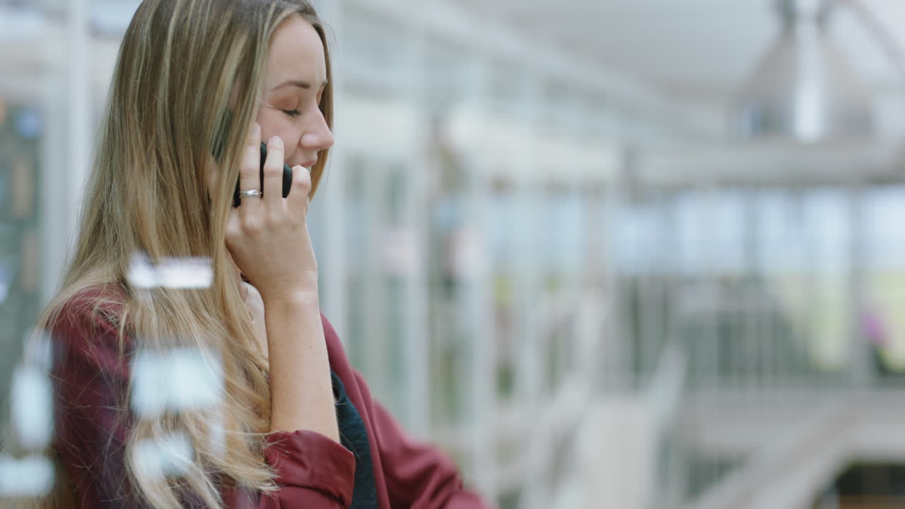donna d'affari che usa uno smartphone che fa una telefonata chattando al cellulare guardando un orologio da polso che si gode la conversazione con un cliente al lavoro in ufficio