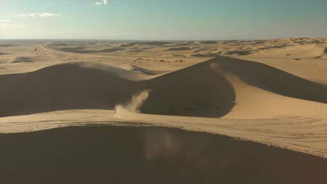 aerial of desert sand dunes with motocross riders and a man running