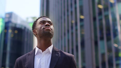 Portrait-Of-Confident-Young-Businessman-Wearing-Suit-Standing-Outside-Looking-Up-At-Offices-In-The-Financial-District-Of-The-City-Of-London-UK-3