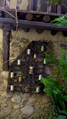 exploring an enchanting outdoor space where a unique wooden frame holds vibrant plant containers against a beautifully textured stone wall, surrounded by lush greenery