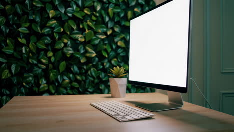 modern workspace with computer and green foliage wall