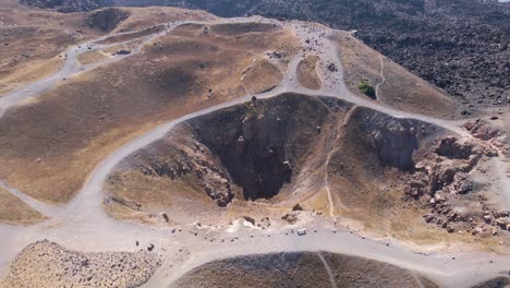 aerial view, approaching and tilting down over volcano crater at santorini island, greece in slow-motion