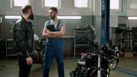 mechaniker und fahrer sprechen in der garage