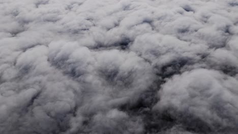 Fast-moving storm cloud layers swirl beneath drone in dark aerial time lapse