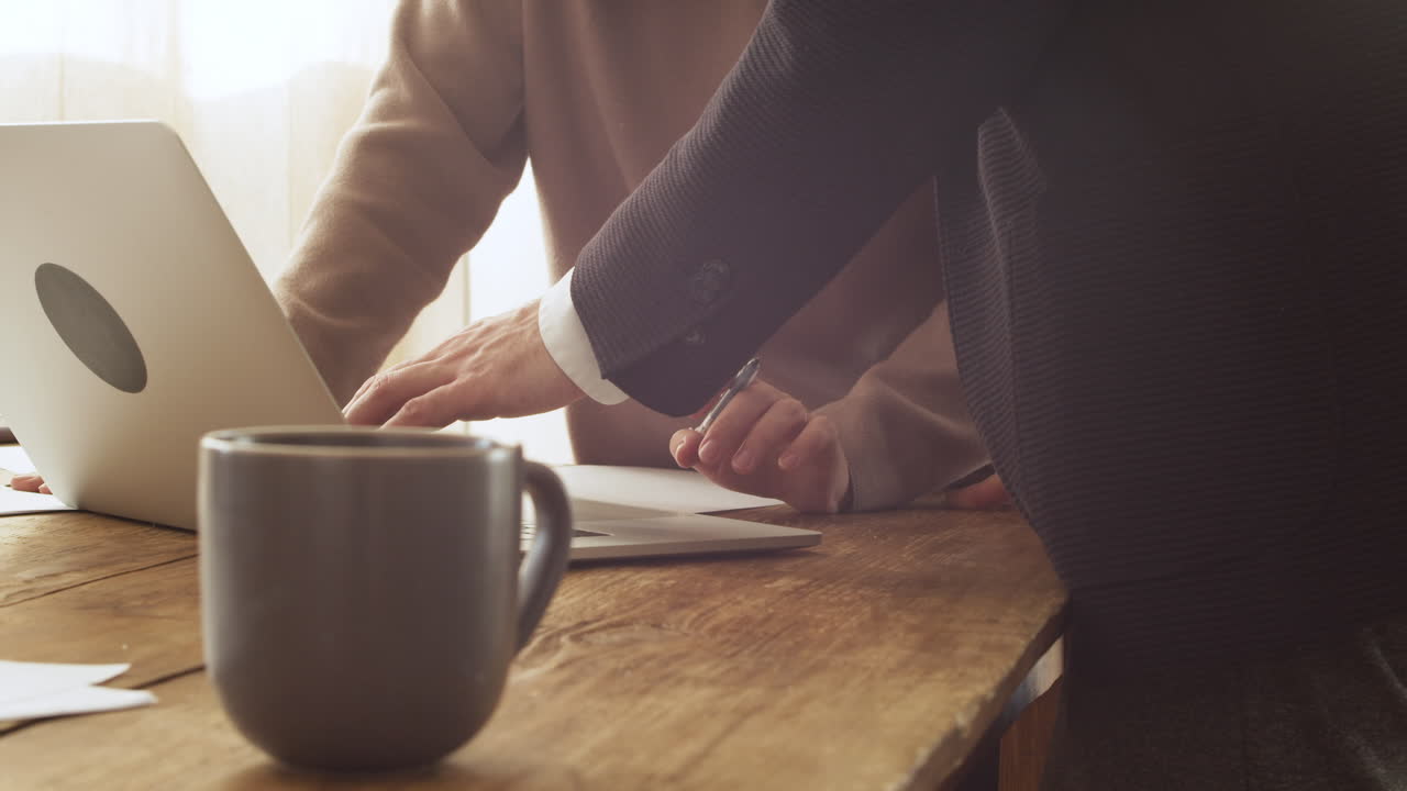 테이블 1에서 랩톱 컴퓨터를 보면서 토론하는 인식할 수 없는 두 동료를 닫습니다.
