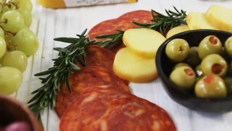 Slices-of-ham-with-cheese,-green-olives-and-herbs