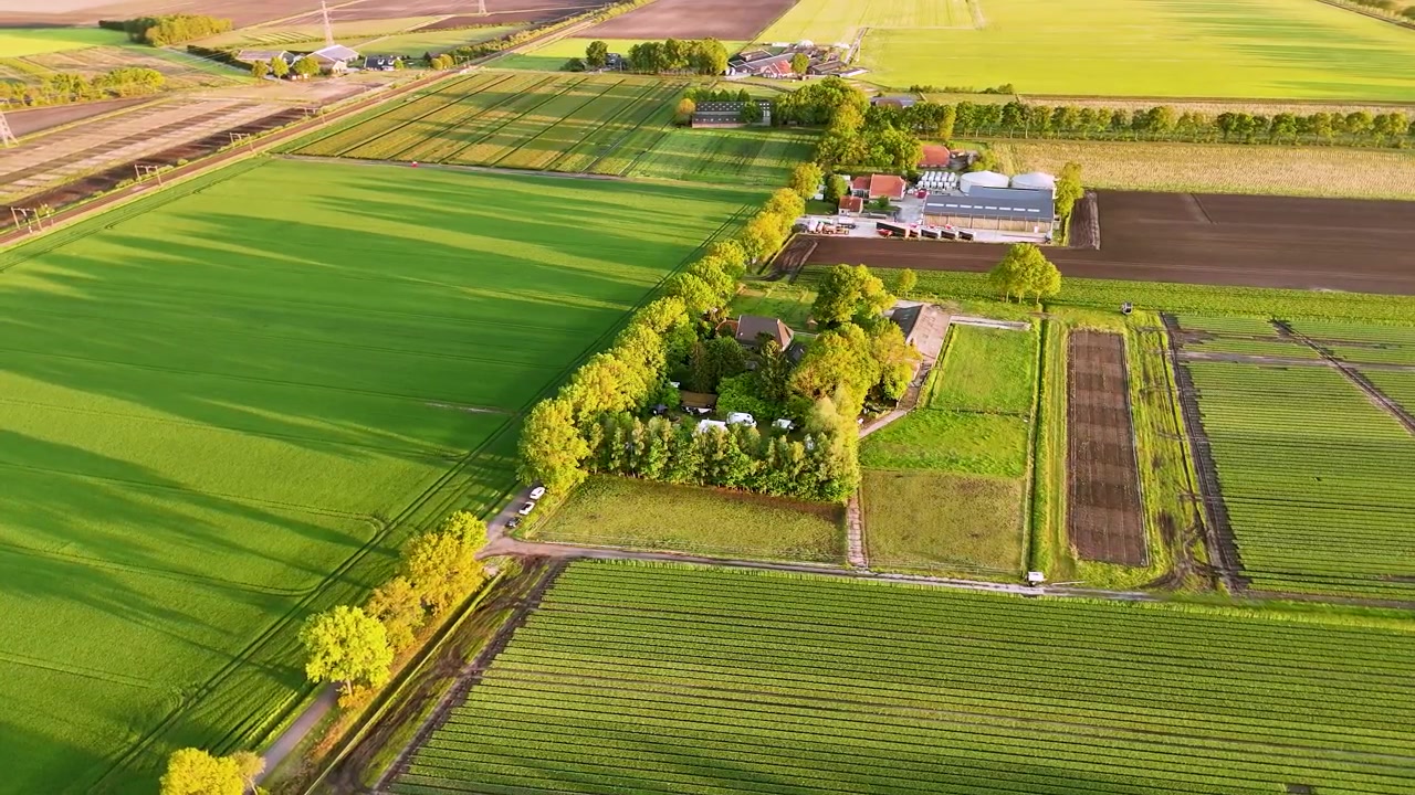 Luftfoto af et bondehus omgivet af frodige grønne marker