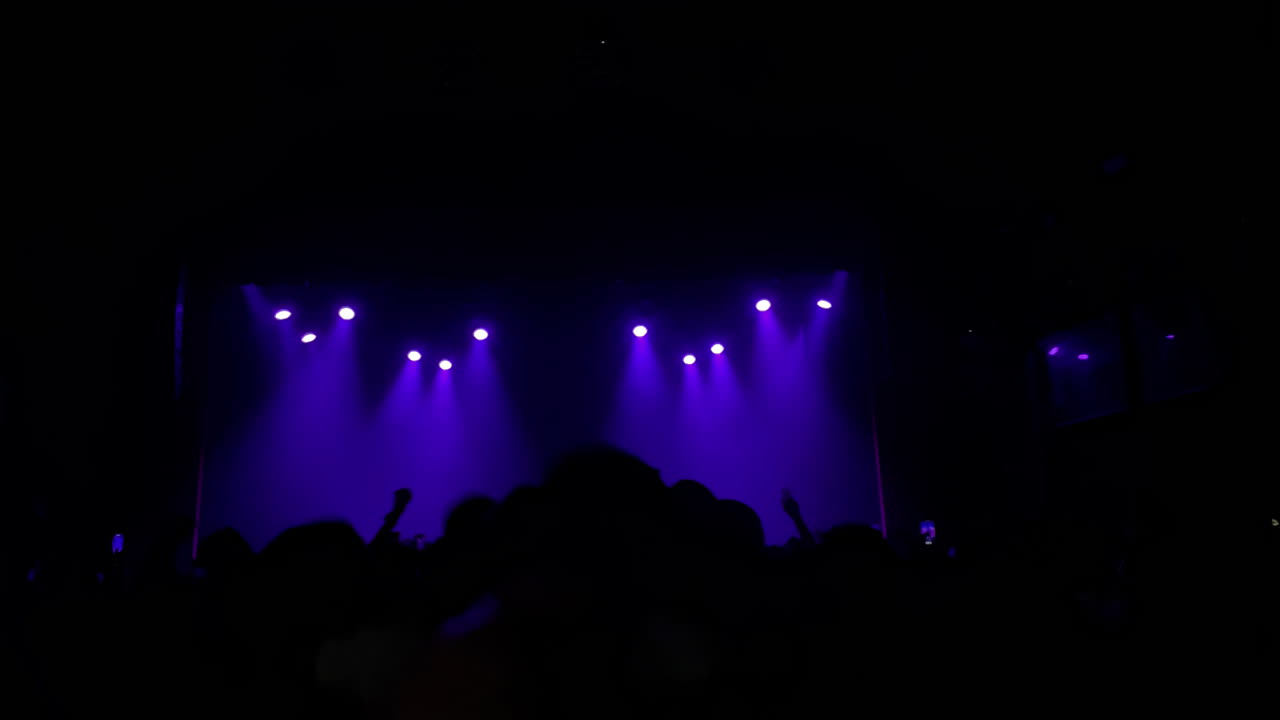 Publikum nyder live musikoptræden med levende lilla lys, der oplyser scenestemningen