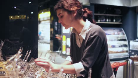 young beautiful brunette girl smells tea before buying it in grocery store