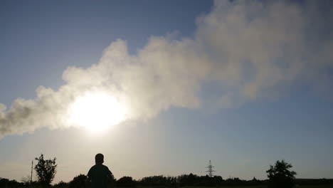 child playing with airplane. small boy playing with paper airplane at sunset near smoky pipes