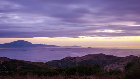 Witness the spectacular sight of a sea hugged by mountains as ships sail through rhythmic waves under thick clouds, Prepare for a mesmerizing timelapse of nature&#039;s grandeur