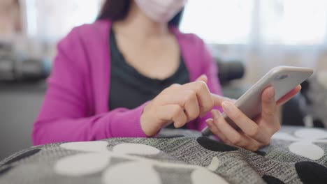 una mujer en primer plano sentada en un sofá sosteniendo un teléfono inteligente para comprar en línea en casa