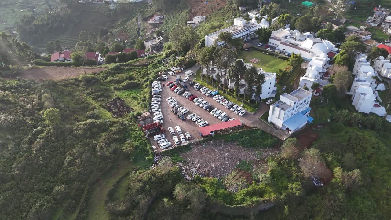 Vista aerea cinematografica che mostra l'altitudine e la fitta vegetazione montana con auto parcheggiate.