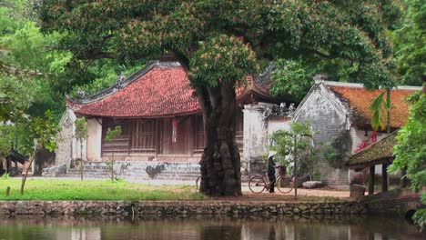 people walk their bicycles past a temple in vietnam