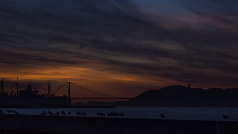 갈매기의 배경 실루엣에 금문교가 있는 샌프란시스코의 아름다운 주황색 일몰, 시간 경과