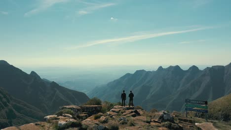 aerial view of two hikers on top of a plateau brazilian canyon with mountains and horizon, canion da ronda, santa catarina, brazil