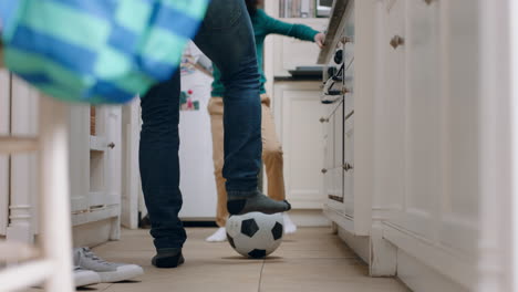 père et fils jouant au football dans la cuisine kicking ballon de football enfant appréciant le jeu avec le père à la maison