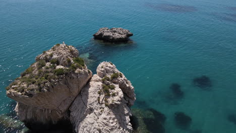 Aerial-Fly-over-Aphrodite's-Rock-in-idyllic-Paphos-shoreline,-Cyprus