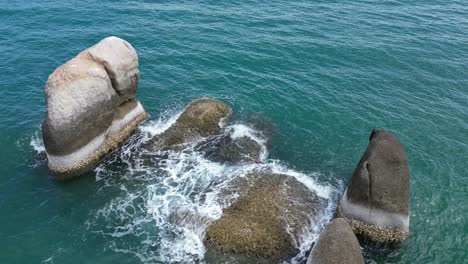 few rocks and stones raised above the sea level in middle of the sea being hit by rough waves