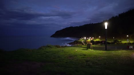 Ocean-waves-crashing-smoothly-to-ligthed-up-park-at-spanish-sea-cliff