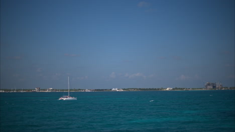 Panning-shot-o-the-coast-and-the-mexican-caribbean-sea-with-boats-and-a-Catamaran-sailing-on-the-water-on-a-sunny-day