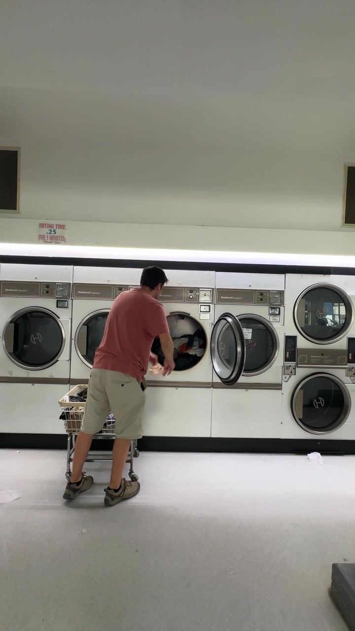 Man loading laundry into an industrial washing machine in a self service laundromat