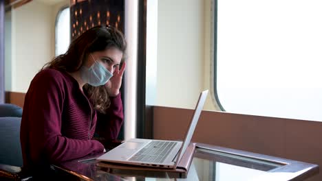 Woman-in-mask-working-on-laptop-on-cruise-ship