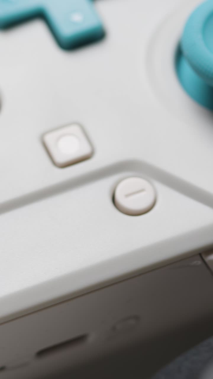 Vertical Video Close Up Hand Picking Up Video Game Controllers White Background 1