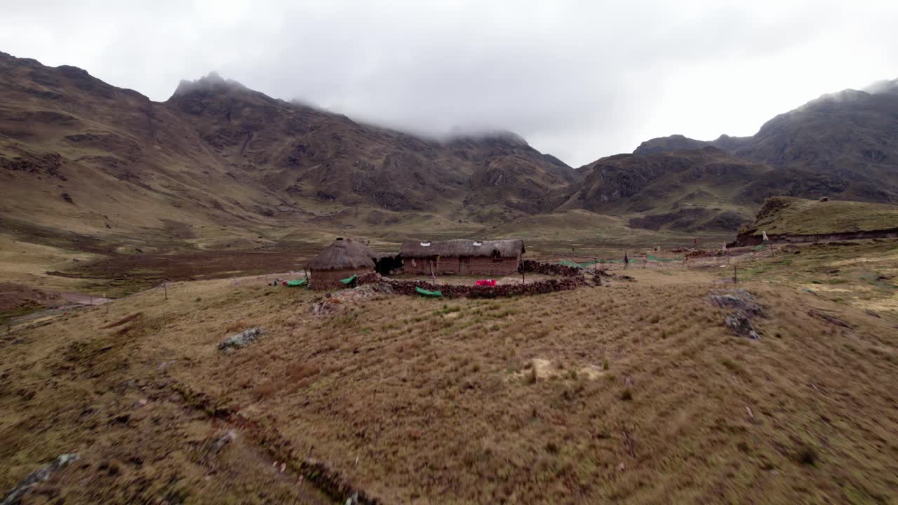 un pueblo remoto está enclavado en un paisaje montañoso, con estructuras de piedra y parches de vegetación.