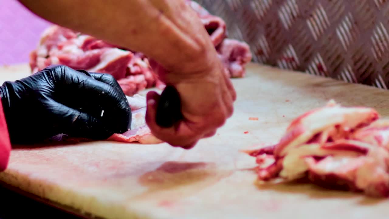A butcher expertly slices meat on a cutting board in a well-lit kitchen, showcasing precision and technique