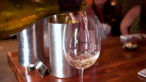 white wine pours into stemmed wine glass at dinner, hd