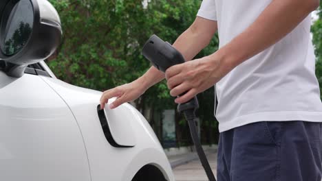 Progressive-man-install-cable-plug-to-his-EV-car-from-home-charging-station.