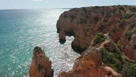 Flying-over-cliff-towards-a-tall-rock-standing-in-the-sea