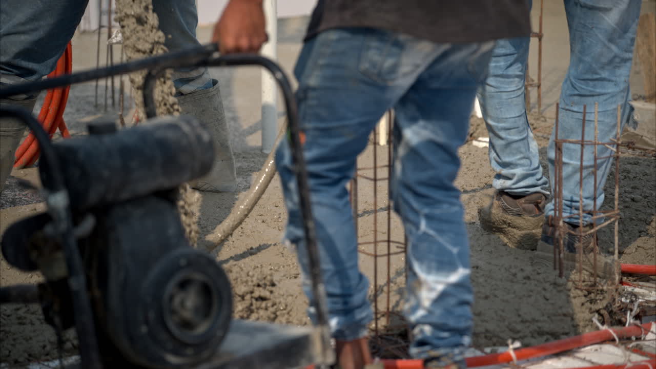 movimiento lento de los trabajadores de la construcción que llevan alrededor de una máquina de vibración de hormigón mientras se vierte una mezcla de concreto fresco para hacer una calva en méxico