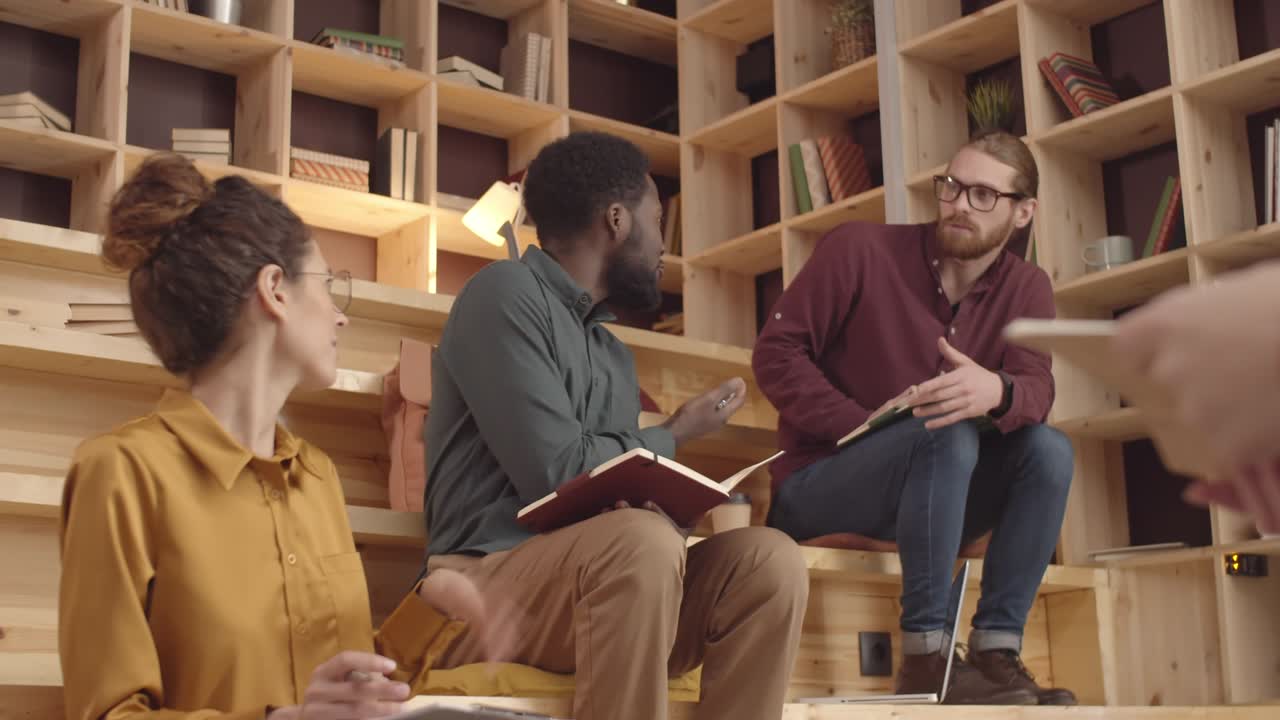 다민족 프로젝트 팀이 코워킹 카페에서 회의에서 논쟁하고 있습니다.