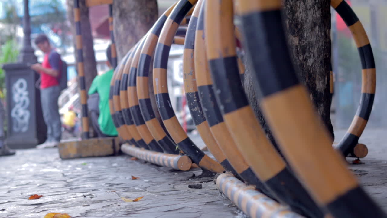 Abstract street view with metal parking installation for bicycles and a man standing texting on a cell phone.