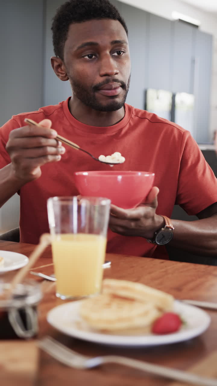 Vertical video of happy african american couple having breakfast at home in slow motion
