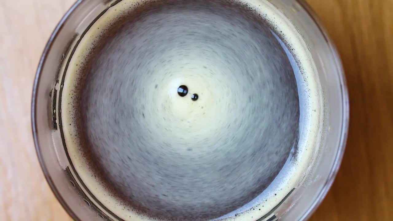 горячий черный кофе в прозрачной кружке с клубящейся пенкой - широкий снимок сверху