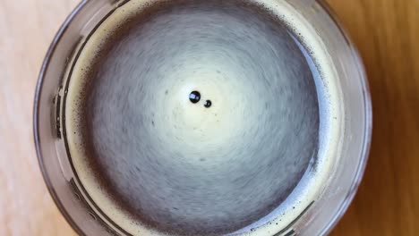 hot black coffee in a clear mug with foam swirling - wide overhead shot